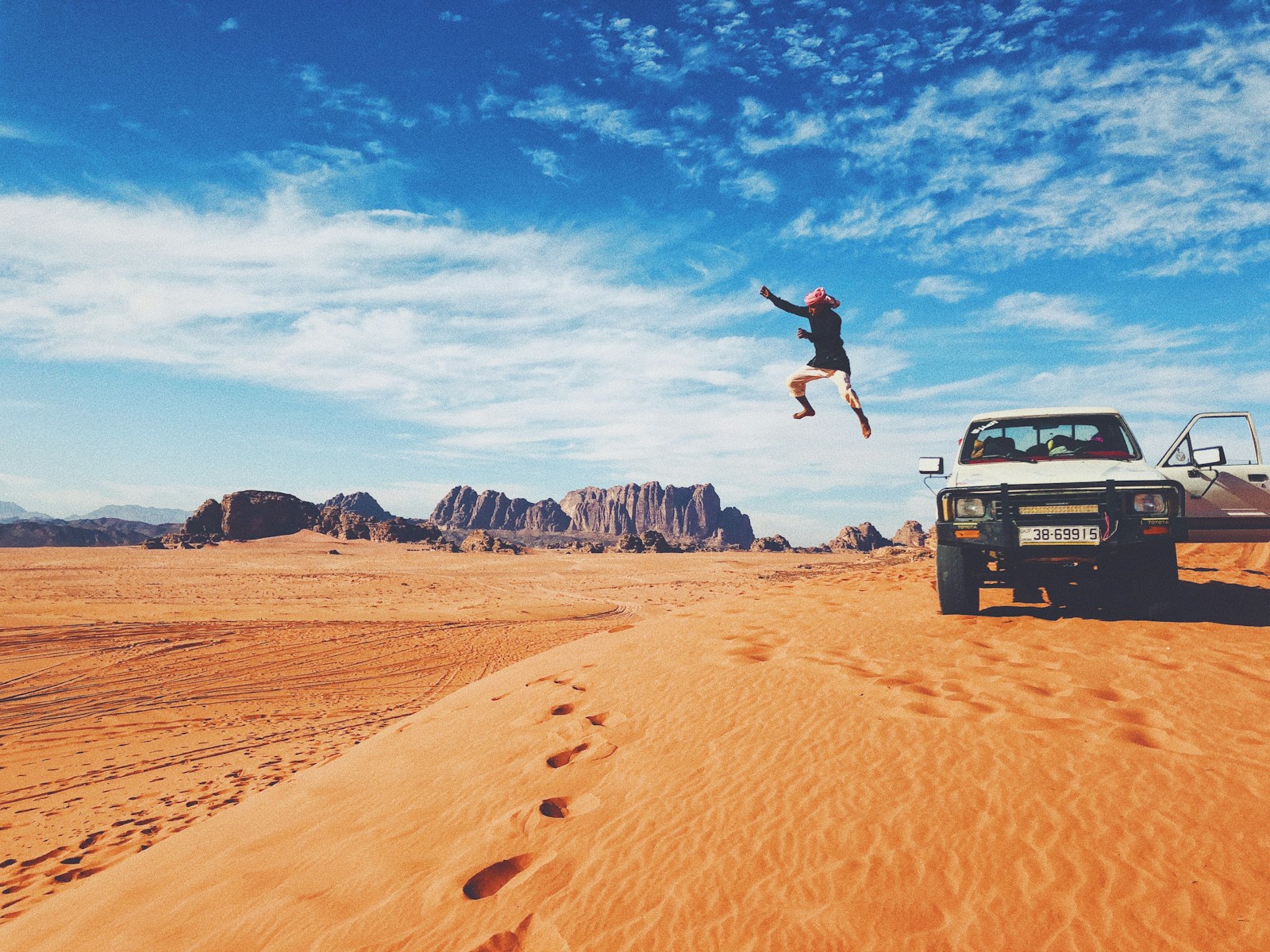 man jumping on brown sand under blue sky during daytime